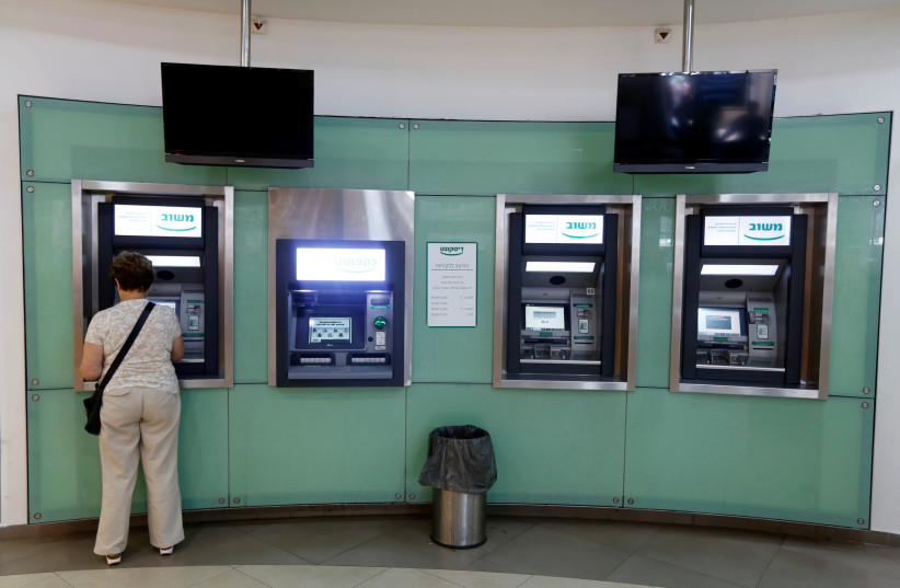 A woman uses an ATM at a branch of Israel Discount Bank in Tel Aviv, Israel July 27, 2016 (photo credit: REUTERS/BAZ RATNER)