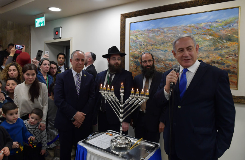Prime Minister Benjamin Netanyahu lights Hanukkah candels with his office workers on Sunday  (photo credit: KOBI GIDEON/PMO)