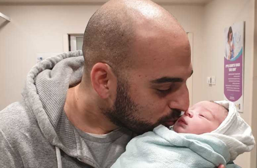 Adam Ben-Naim kissing his newborn son (credit: Courtesy)