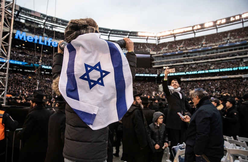 Orthodox Jews sing and dance during the 13th Siyum HaShas, a celebration marking the completion of the Daf Yomi, a seven-and-a-half-year cycle of studying texts from the Talmud, the canon of Jewish religious law, at the MetLife Stadium in East Rutherford, New Jersey, U.S., January 1, 2020 (photo credit: REUTERS/JEENAH MOON)