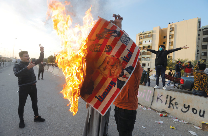 A PROTESTER holds a burning placard with an illustration of US President Donald Trump outside the US Embassy in Baghdad on Wednesday.  (photo credit: KHALID AL MOUSILY / REUTERS)