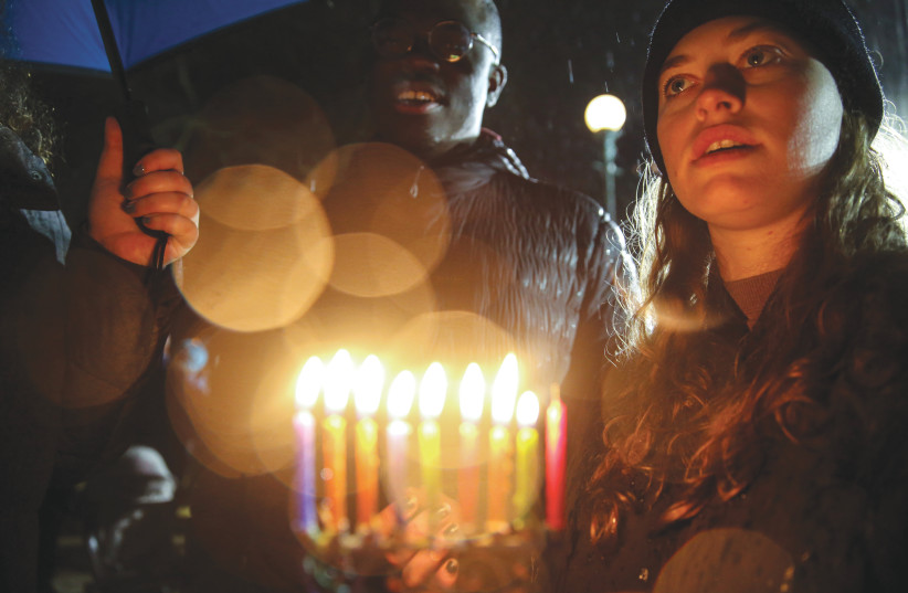 A WOMAN holds a hanukkiah during a solidarity rally in Brooklyn on December 29 following the attack in Monsey on Jews who were celebrating the seventh night of Hanukkah at the home of a rabbi. (photo credit: AMR ALFIKY/ REUTERS)