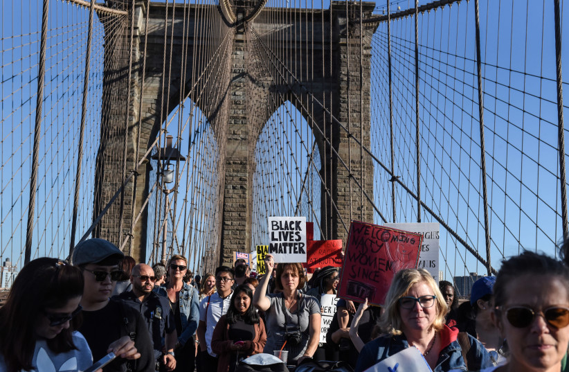 A person carrying a Black Lives Matter sign participates in a protest called March for Racial Justice while walking over the Brooklyn Bridge in New York City, U.S. October 1, 2017 (photo credit: REUTERS/STEPHANIE KEITH)