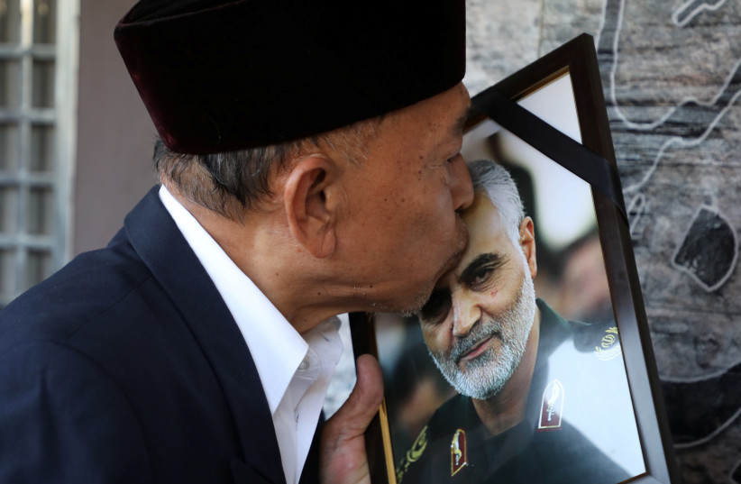 A man kisses a picture of Iranian Major-General Qassem Soleimani, who was killed in a airstrike near Baghdad, outside the Embassy of Iran in Kuala Lumpur, Malaysia, January 7, 2020 (photo credit: REUTERS/LIM HUEY TENG)