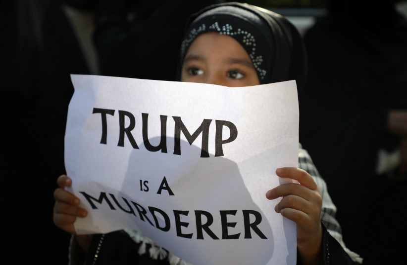A girl holds a sign reading “Trump is a murderer” during a condolence ceremony for Iranian Major-General Qassem Soleimani, who was killed in a airstrike near Baghdad, outside the Embassy of Iran in Kuala Lumpur, Malaysia, January 7, 2020 (photo credit: REUTERS/LIM HUEY TENG)