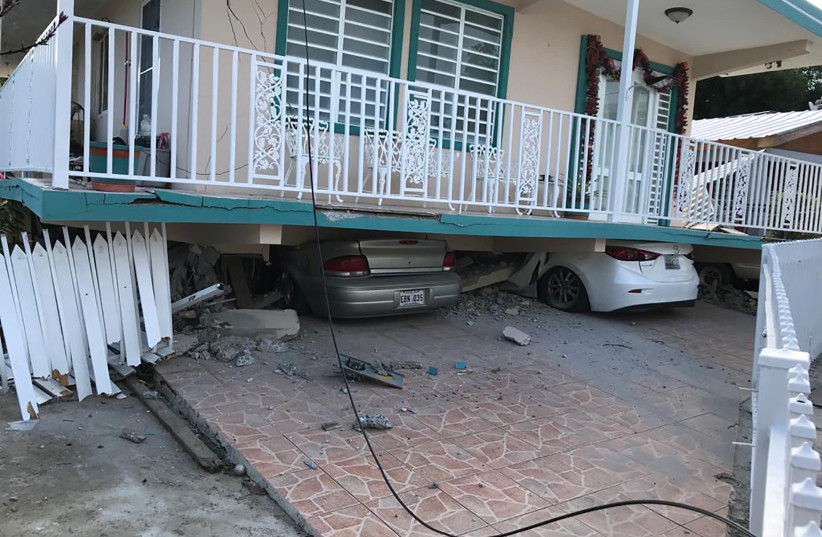 Cars lie under a collapsed house after an earthquake in Guanica, Puerto Rico January 6, 2020 (photo credit: REUTERS/RICARDO ORTIZ)