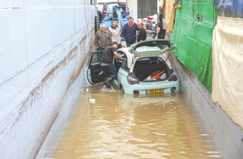 People try to release a car that was stuck due to heavy rains in Jaffa on Sunday  (photo credit: FLASH90)