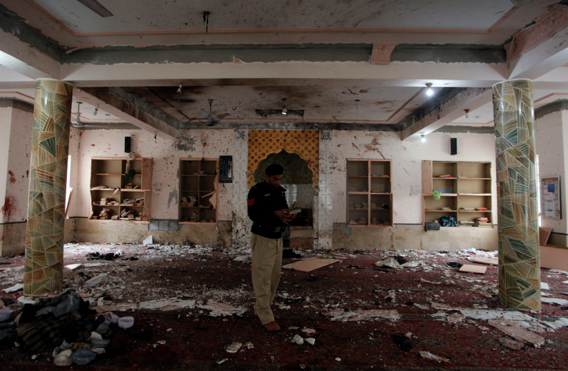 A police officer stands amidst the damages as he is surveying and collecting evidence from the site of a bomb blast in a mosque in Quetta, Pakistan January 11, 2020 (photo credit: REUTERS/NASEER AHMED)