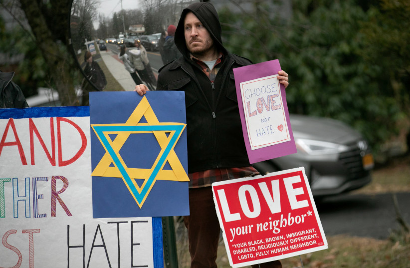 A man holds a sign outside the home of rabbi Chaim Rottenberg in Monsey, New York, U.S., December 29, 2019 (photo credit: REUTERS/JEENAH MOON)