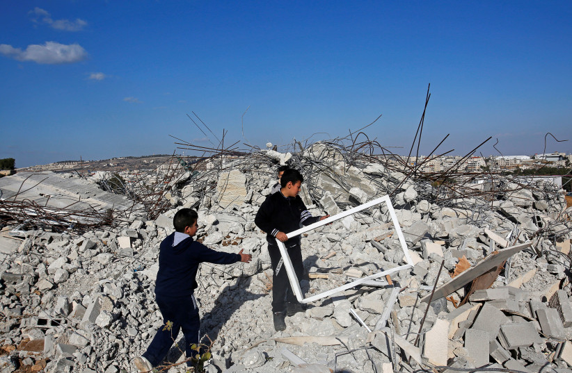 Palestinian boys inspect a house that was demolished by Israeli forces in al-Khader village near Bethlehem, in the West Bank December 16, 2019. (photo credit: MUSSA QAWASMA/REUTERS)