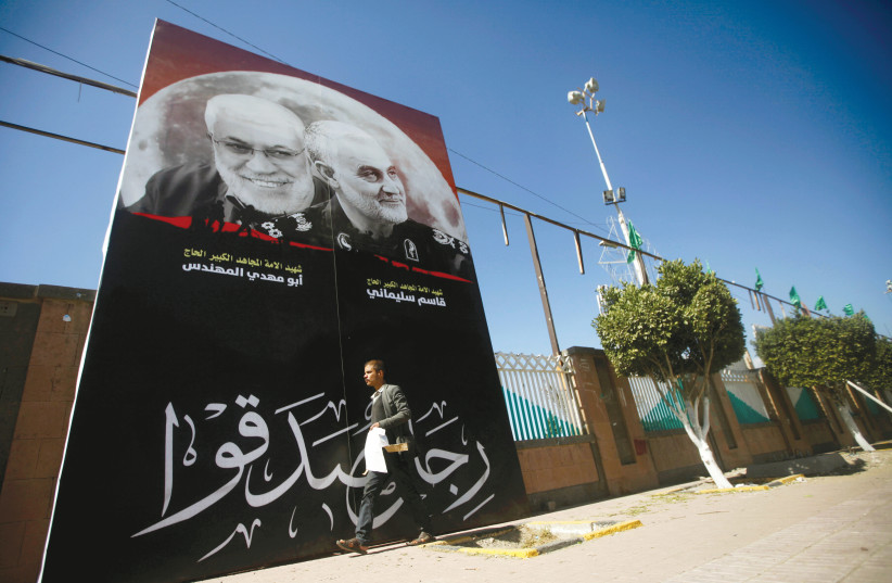 A MAN PASSES a billboard with posters of Iranian General Qassem Soleimani, head of the elite Quds Force, and Iraqi militia commander Abu Mahdi al-Muhandis, who were killed in an air strike at Baghdad airport, in Sanaa, Yemen January 9. (photo credit: MOHAMED AL-SAYAGHI/REUTERS)