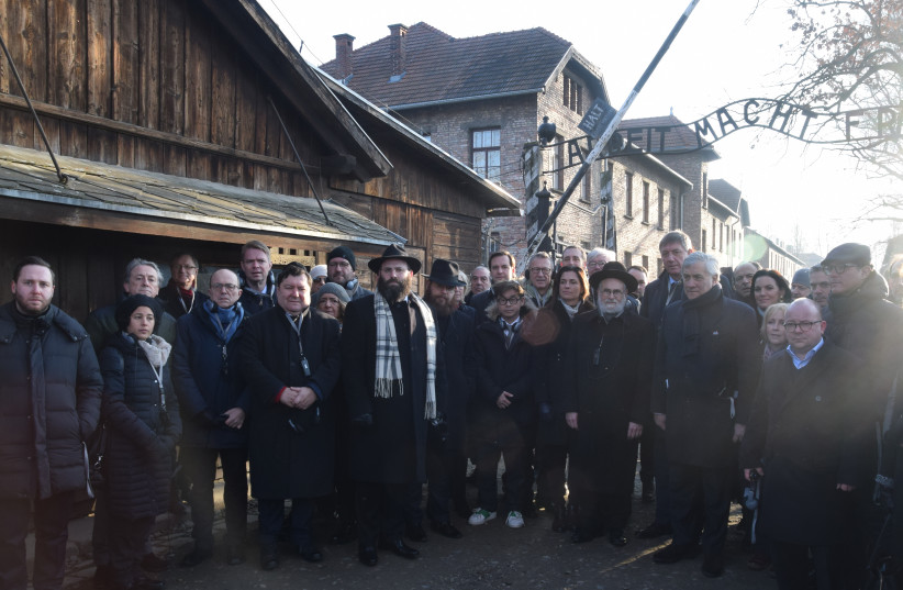Members of the European Union delegation under the entrance to the Auschwitz concentration camp (photo credit: YONI RYKNER)