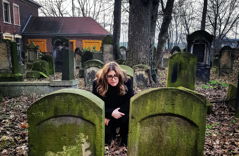 Jerusalem Post reporter Ilanit Chernick kneels next to what's believed to be her great-great-great grandparents graves in the New Jewish Cemetery in Krakow, Poland. (photo credit: JONNY DANIELS)