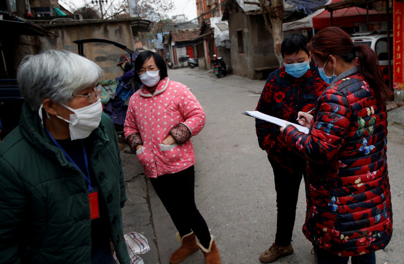 Members of a neighbourhood committee register locals and ask about therr travel history in Jiujiang, Jiangxi province, China, as the country is hit by an outbreak of novel coronavirus. February 2, 2020 (photo credit: REUTERS/THOMAS PETER)