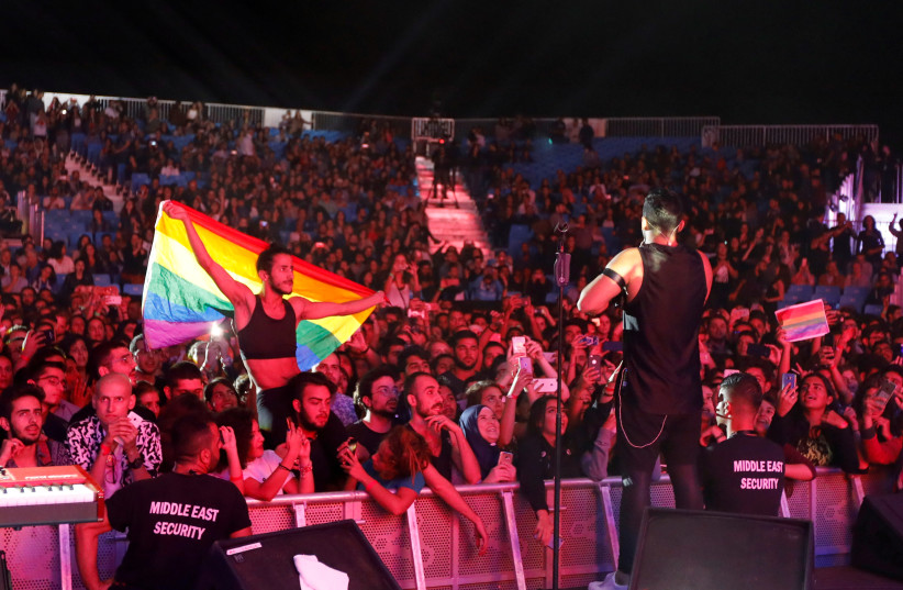 FILE PHOTO: A fan of Lebanese alternative rock band Mashrou' Leila holds a rainbow flag during their concert at the Ehdeniyat International Festival in Ehden town, Lebanon August 12, 2017. Picture taken August 12, 2017 (photo credit: REUTERS/JAMAL SAIDI/FILE PHOTO)
