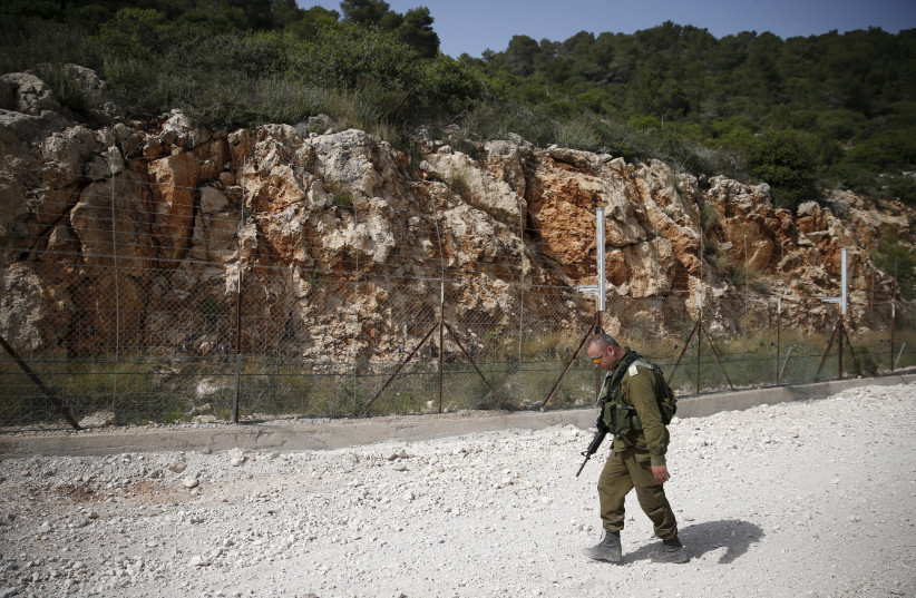An Israeli soldier walks near the area where the Israeli army is excavating part of a cliff to create an additional barrier along its border with Lebanon, near the community of Shlomi, 2016 (photo credit: RONEN ZVULUN/REUTERS)