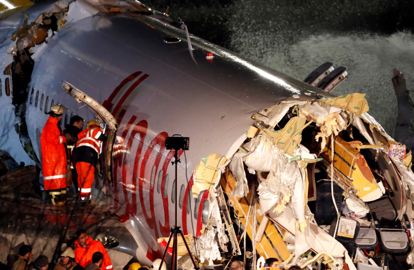 First responders look inside the Pegasus Airlines Boeing 737-86J plane, after it overran the runway during landing and crashed, at Istanbul's Sabiha Gokcen airport, Turkey February 5, 2020 (photo credit: REUTERS/MURAD SEZER)