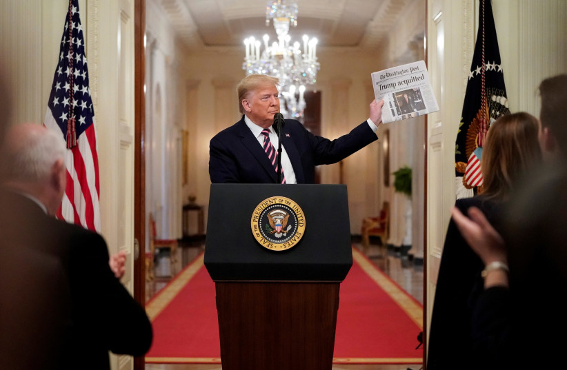 U.S. President Donald Trump holds up a copy of the Washington Post's front page showing news of Trump's acquittal in his Senate impeachment trial, as he delivers a statement about his acquittal in the East Room of the White House in Washington, U.S., February 6, 2020. (photo credit: JOSHUA ROBERTS / REUTERS)