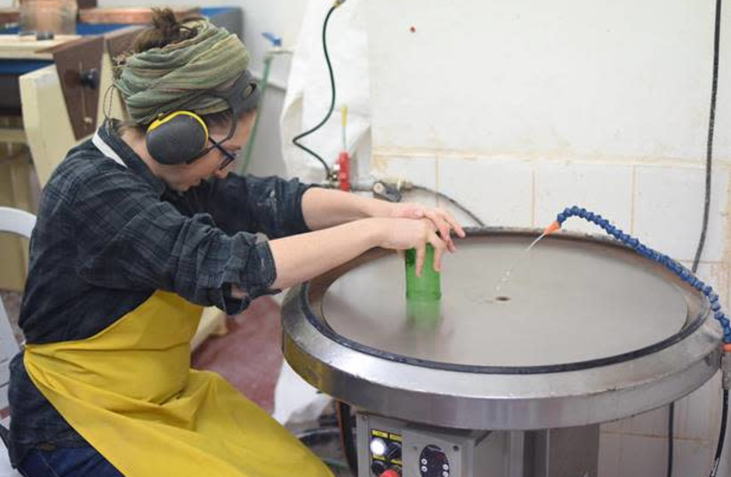 Stephanie Jude, Student in the Department of Ceramics and Glass Design at Bezalel Academy, smoothing the sharp glass edges using a horizontal grinding wheel at the “CupAthon” event, ahead of Tu Bishvat 2020. (photo credit: NOA GOLDBLAT)