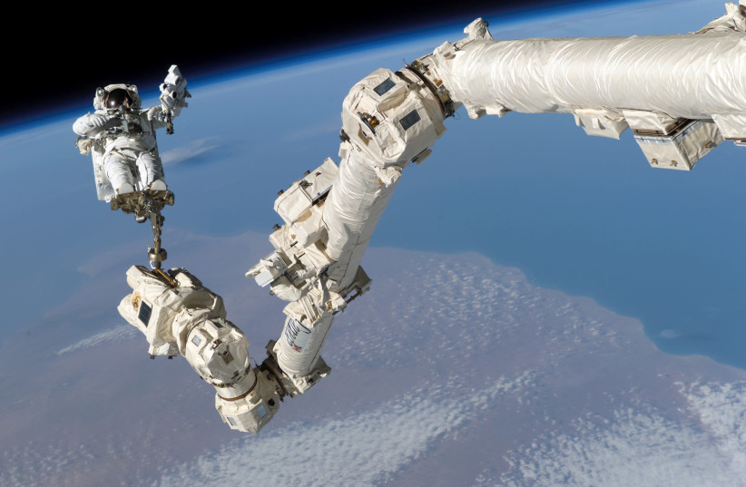 NASA astronaut Stephen K. Robinson is anchored to a foot restraint on the International Space Station. (photo credit: NASA/HANDOUT VIA REUTERS)