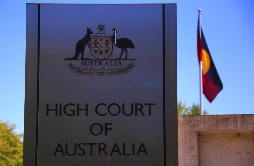 The Australian Aboriginal flag flies behind a sign outside the High Court of Australia building in Canberra. (photo credit: DAVID GRAY / REUTERS)