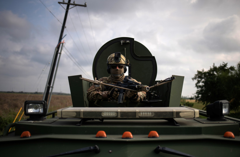 An agent with the U.S. Border Patrol Tactical Unit (BORTAC) holds his weapon from an armored vehicle ahead of exercises in Mission, Texas, November 8, 2018. Picture taken on November 8, 2018. (photo credit: REUTERS/ADREES LATIF)