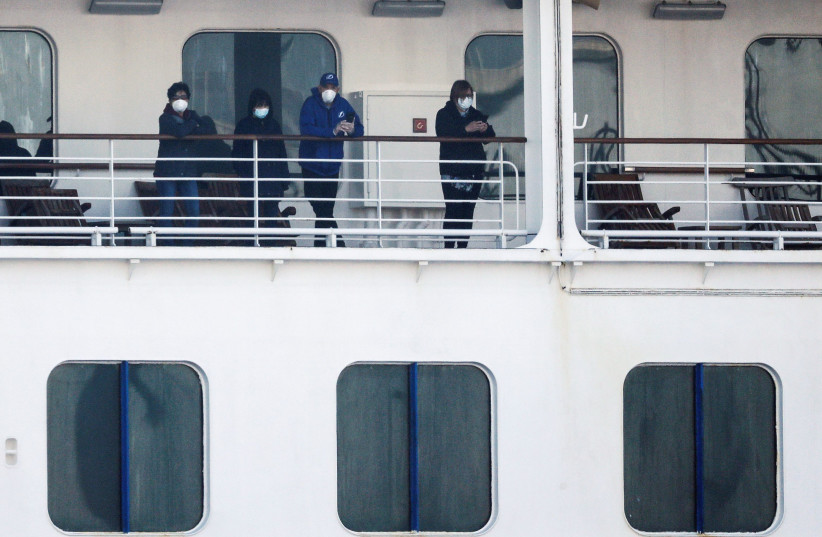 Passengers wearing mask are seen on the cruise ship Diamond Princess, as the vessel's passengers continue to be tested for coronavirus, at Daikoku Pier Cruise Terminal in Yokohama, south of Tokyo, Japan February 13, 2020 (photo credit: REUTERS/KIM KYUNG-HOON)