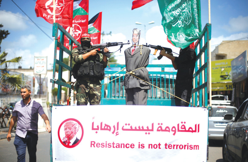 Des MEMBRES du Front populaire de libération de la Palestine (FPLP) pointent leurs armes sur une effigie représentant le président américain Donald Trump alors qu'ils conduisent un camion lors d'une manifestation dans la ville de Gaza.  (crédit : REUTERS)