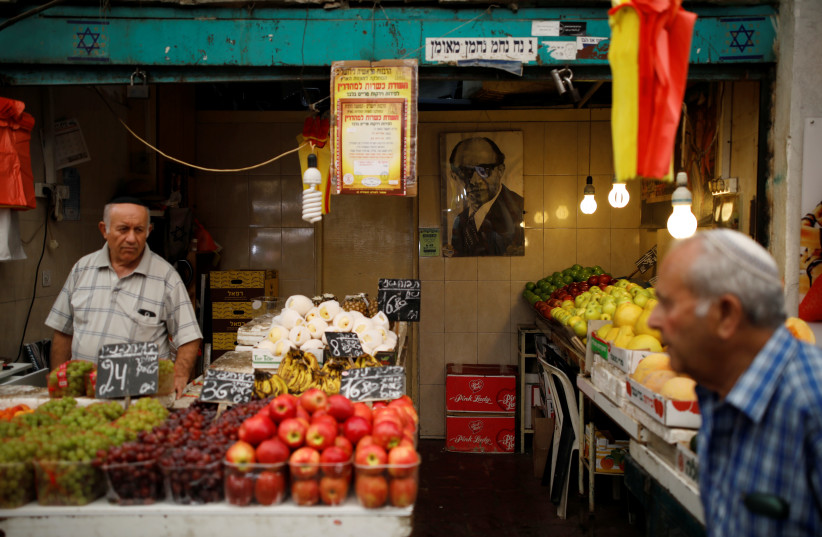 A man walks past a fruit and vegetable stall in a market in Jerusalem (photo credit: REUTERS/AMIR COHEN)