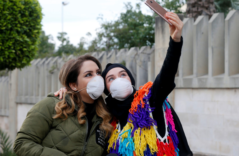 People wearing face masks take a picture with a mobile phone outside Rafik Hariri hospital, where Lebanon's first coronavirus case is being quarantined, in Beirut (photo credit: REUTERS/MOHAMED AZAKIR)
