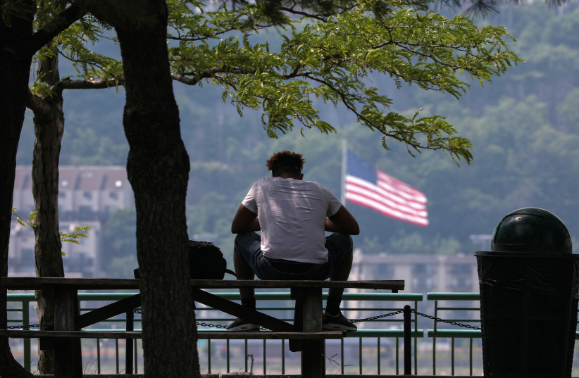 A man sits in the shade at Riverbank State Park during very hot weather in the Washington Heights section of Manhattan in New York City, New York, U.S. (photo credit: REUTERS)