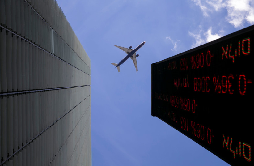 A plane flys above an electronic board displaying market data outiside the Tel Aviv Stock Exchange, in Tel Aviv, Israel January 29, 2017. (photo credit: BAZ RATNER/REUTERS)