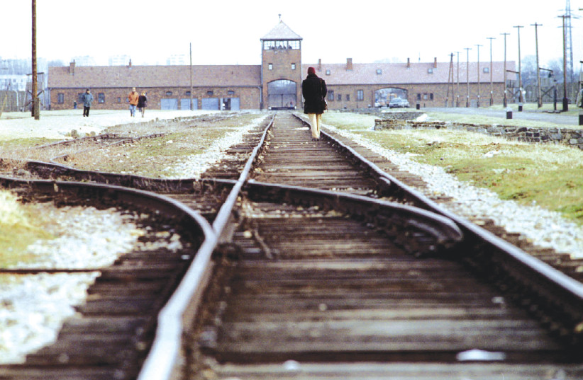 VISITORS WALK along the railway track at the main gate of the Auschwitz Birkenau concentration camp. (photo credit: REUTERS)