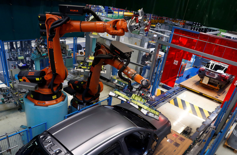 A robot engineered by Kuka adjusts a windscreen in a fully automated process on a model of the A-class production line of German car manufacturer Mercedes Benz at the Daimler factory in Rastatt, Germany, February 4, 2019. Picture taken on February 4, 2019.  (photo credit: REUTERS)