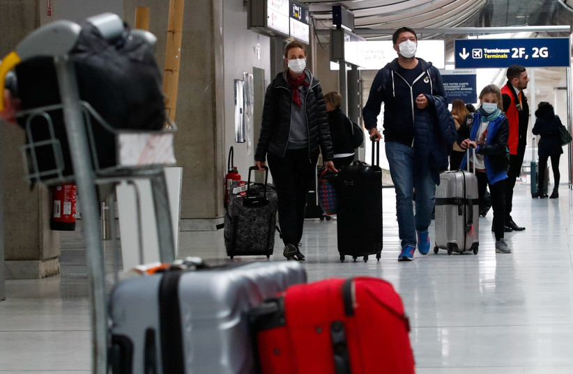 People wearing protective face masks arrive at Charles de Gaulle airport near Paris, France. (photo credit: REUTERS/GONZALO FUENTES)