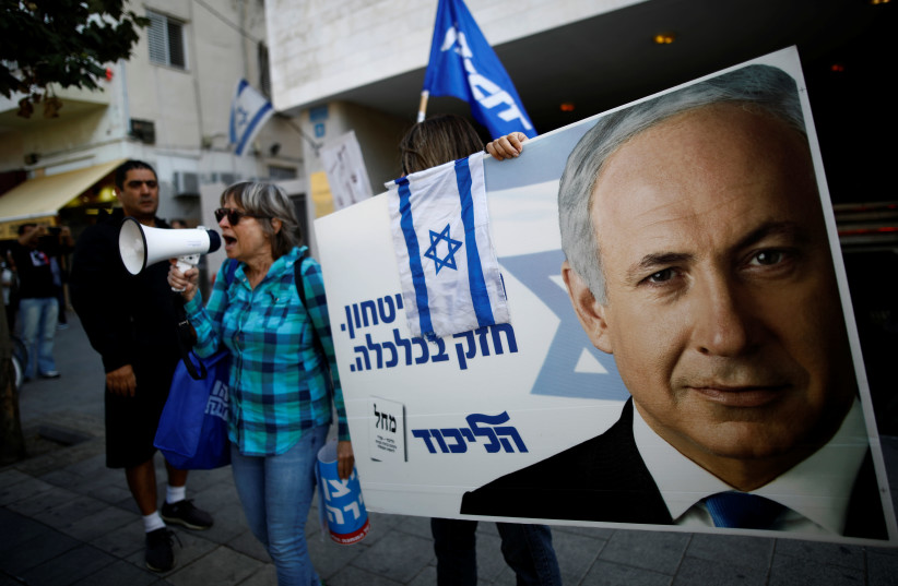 Supporters of Israeli Prime Minister Benjamin Netanyahu protest outside Likud Party headquarters in Tel Aviv, Israel November 22, 2019. The placards in Hebrew read, "Strong in security, strong in Economy  (photo credit: REUTERS/CORINNA KERN)
