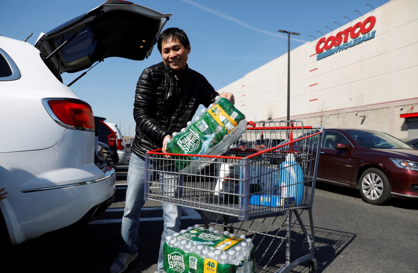 A man loads water into his car in the Costco parking lot, after the first confirmed case of coronavirus was announced in New York State, in the Brooklyn borough of New York City, New York, U.S., March 2, 2020. (photo credit: ANDREW KELLY / REUTERS)