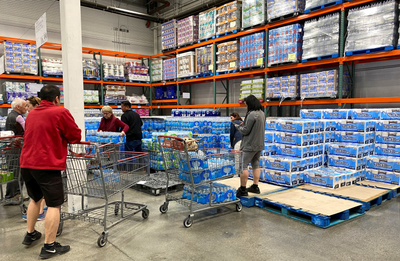 Customers load shopping carts with toilet paper and water at a Costco store...