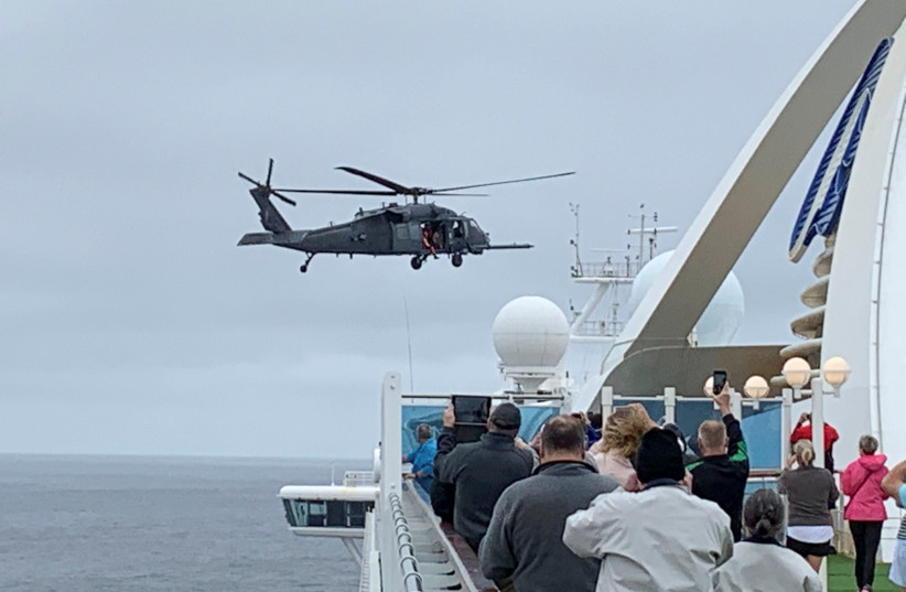 Passengers on board the Grand Princess cruise ship off San Francisco watch while a U.S. military helicopter hovers above the deck (photo credit: REUTERS)