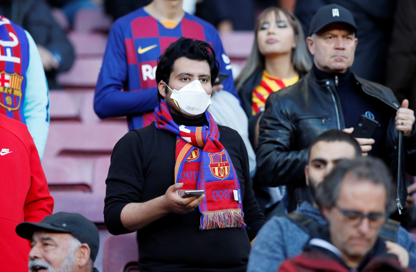 A Barcelona fan wears a mask before the match due to the recent coronavirus outbreak, March 7, 2020 (photo credit: REUTERS/ALBERT GEA)