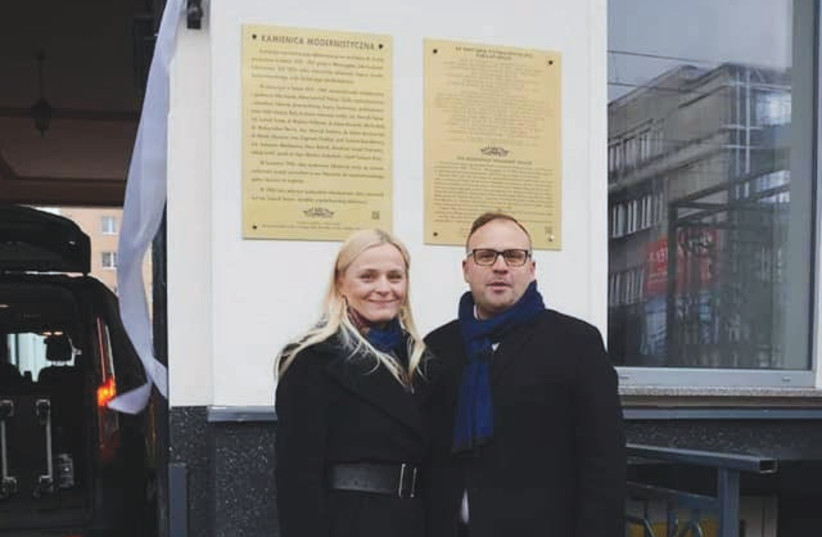 MARIUSZ AND Patricycja Etryk stand in front of their building bearing the memorial plaque with the names of Jews who lived there. (photo credit: ALON GOLDMAN)