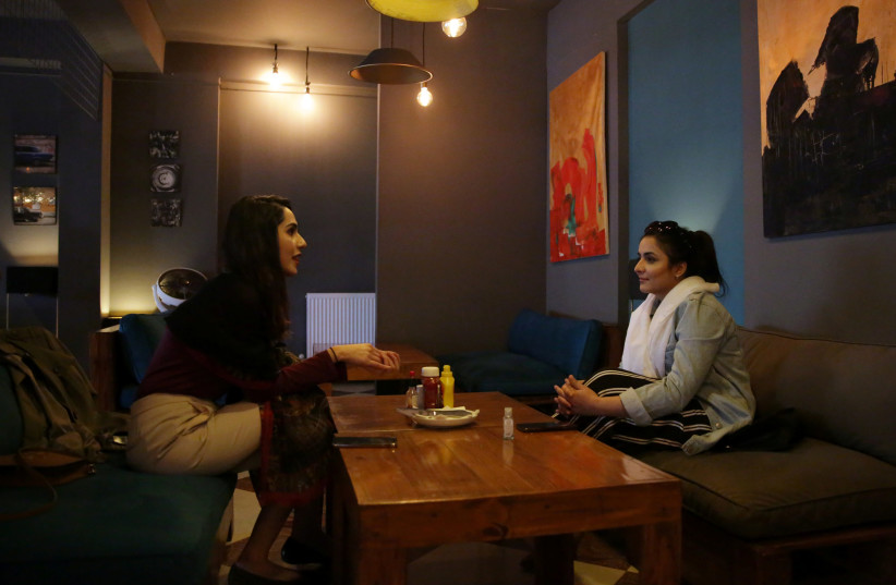 Women chat as they sit at a burger shop in Kabul (photo credit: REUTERS)