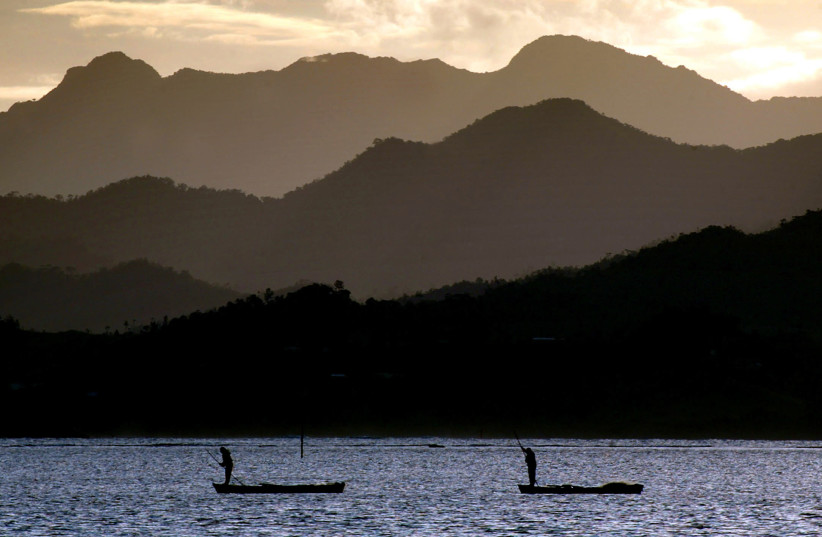 Fijian fishermen stand in their boats as they work in front of an island's mountain range near Suva April 29, 2004. Canoes are still used by fishermen as a means of getting to deeper waters in the South Pacific Island nation that is made up of more than 300 islands scattered across 500,000 square-ki (photo credit: REUTERS)