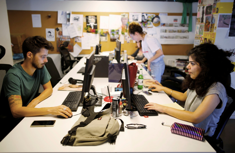 Employees work at the offices of "Time Out Tel Aviv" magazine in Tel Aviv, Israel September 28, 2017. (photo credit: AMIR COHEN/REUTERS)