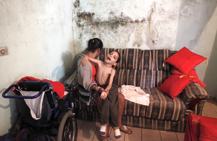 A WOMAN dresses her son, who suffers from a neurological disorder, in Sao Paulo in 2012. (photo credit: REUTERS)