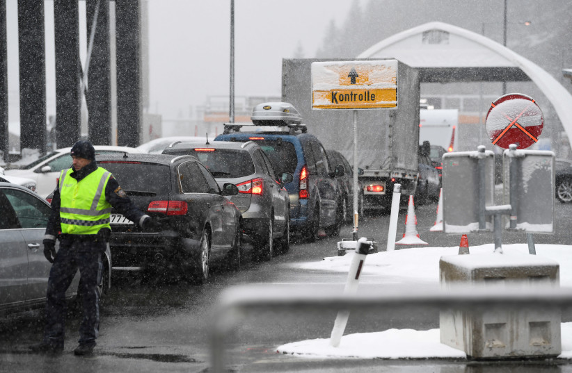A police officer guides cars waiting in line in front of a tent where medics check the temperature of people coming from Italy due to the spreading of the coronavirus disease (COVID-19) at the Brenner Pass border between Italy and Austria, March 10, 2020 (photo credit: REUTERS/ANDREAS GEBERT)