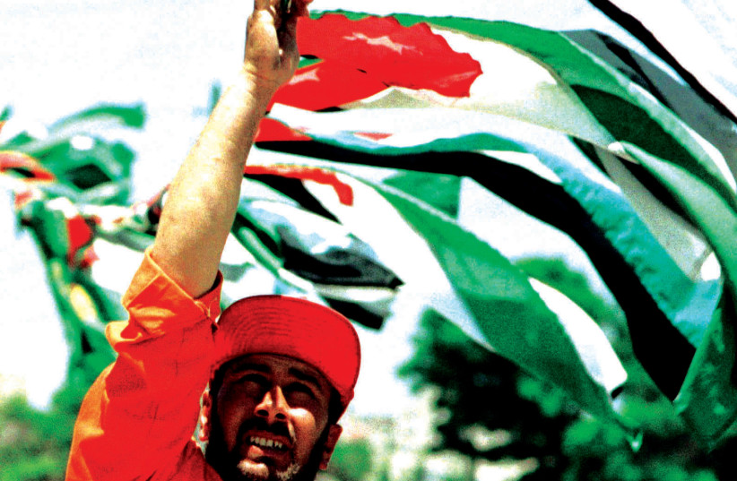 JORDANIAN man lifts the country’s flag at a celebration in the 1990s. (photo credit: REUTERS)