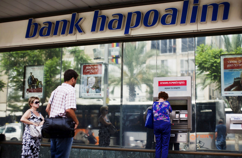 A woman uses an automated teller machine (ATM) outside a Bank Hapoalim branch in Tel Aviv, Israel May 30, 2013 (photo credit: REUTERS/NIR ELIAS/FILE PHOTO)