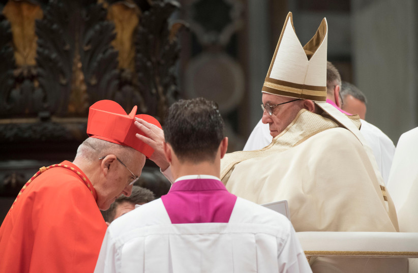 Pope Francis gives the traditional biretta hat to new cardinal Carlos Osoro Sierra of Spain during a consistory ceremony to install 17 new cardinals in Saint Peter's Basilica at the Vatican (photo credit: REUTERS)