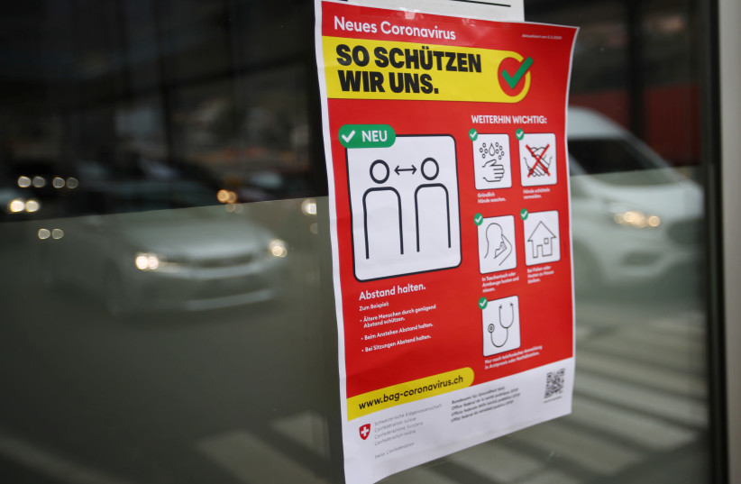 Safety measures poster is pictured at the Swiss-Italian border during the outbreak of COVID-19 in Chiasso, Switzerland (photo credit: DENIS BALIBOUSE/REUTERS)